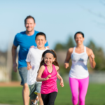 Family of four running with little girl in front then son and parents. 