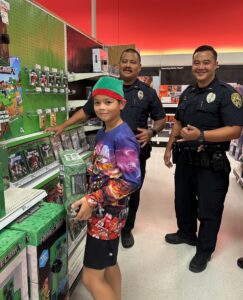 boy holding video game with two officers behind him during Heroes and Helpers event.