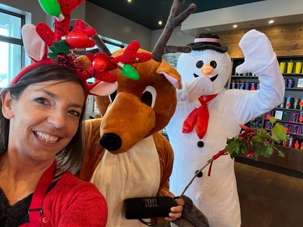 Women posing in front of two people in costume - one a reindeer and the other a snowman.