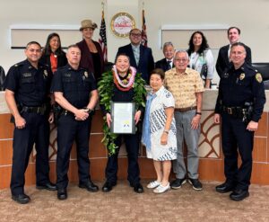 Group photo of Hawaii County Council members and police officers with Detective Donovan Kohara receiving Haweo award. 