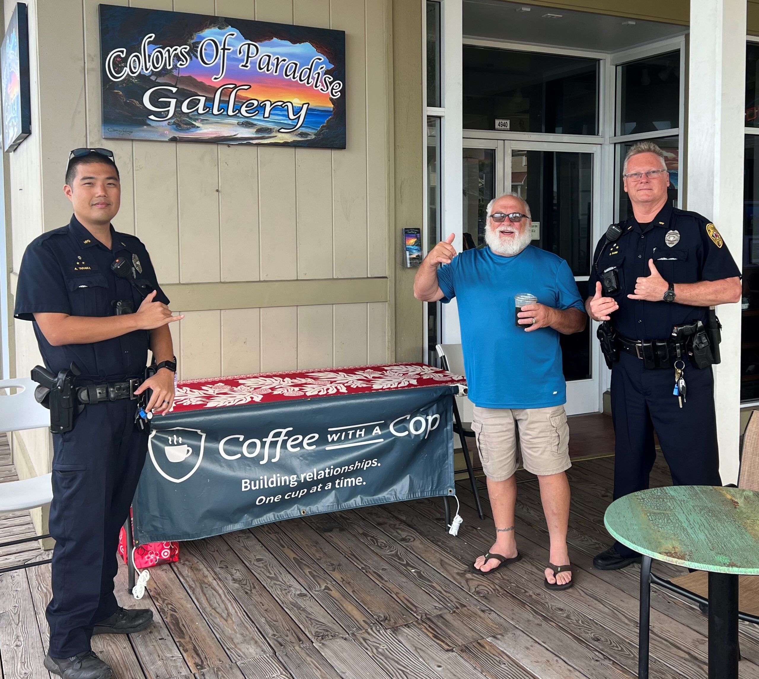 Two police officers with grey haired man standing by Coffee With a Cop banner.