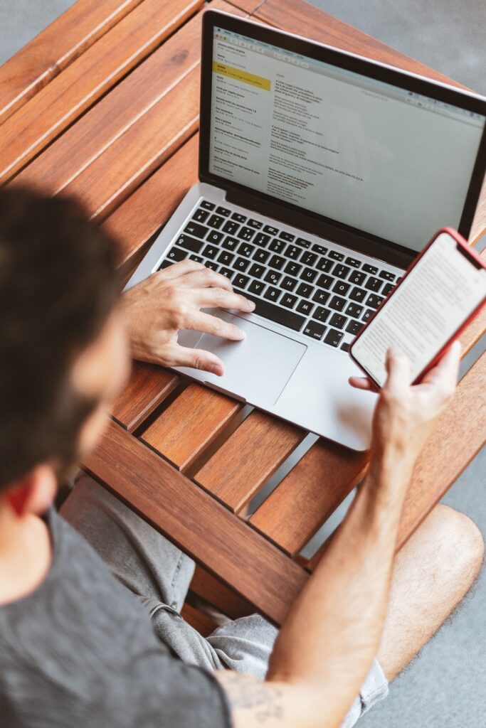 Man on computer and also holding phone